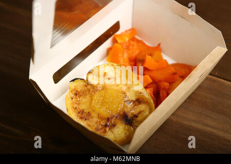 Lieferung von Dessert aus dem gebackenen Kürbis und Apfel in einem Papier container. Einen schnellen Snack außerhalb des Hauses. Kalorienarmes Dessert, eine gesunde Ernährung für Th Stockfoto