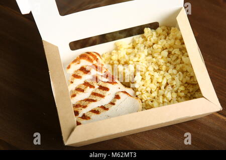 Gegrilltes Hähnchen mit Scheiben, mit Bulgur in einem Papier container. Lieferung nach Hause, einen schnellen Snack. Kalorienarme, diätetische Lebensmittel für einen gesunden Lebensstil. Stockfoto