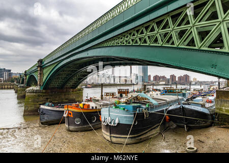 Boote bei Ebbe auf der Themse, unter dem Bogen von Battersea Eisenbahnbrücke, Battersea, London, Vereinigtes Königreich Stockfoto