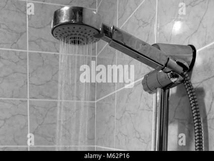 Schwarz-weiß Bild von der Dusche im Bad. Von einem schönen, verchromte Duschkopf unter großem Druck mit Wasser übergossen. Stockfoto