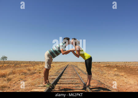 Junges Paar Küssen auf die Bahn in der Wüste im Outback Australiens. Backpacker Liebhaber Konzept Stockfoto