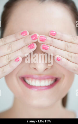 Smiling woman covering eyes with hands Stockfoto