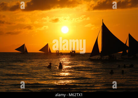 Silhouette von Segelbooten und Menschen bei Sonnenuntergang auf White Beach von Boracay, Philippinen. Paradies Urlaub, Reise Ziel Konzept Stockfoto