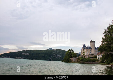 Duingt Schloss mit Berglandschaft und bewölkter Himmel neben dem See von Annecy, in der Nähe von Annecy. Departement Haute-Savoie, Frankreich. Stockfoto