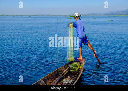 Ein Fischer, stehend auf seinem Boot, Angeln ist die traditionelle Art und Weise auf dem Inle See Stockfoto