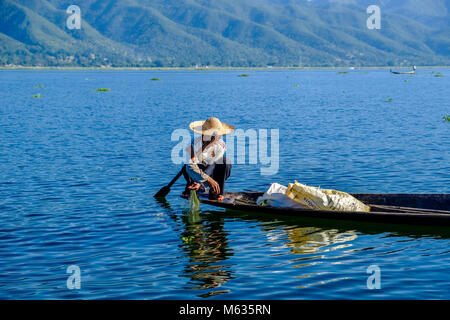 Ein Fischer, saß auf seinem Boot, Angeln ist die traditionelle Art und Weise auf dem Inle See Stockfoto