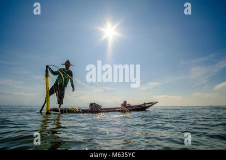 Ein Fischer, stehend auf seinem Boot, Angeln ist die traditionelle Art und Weise auf dem Inle See Stockfoto