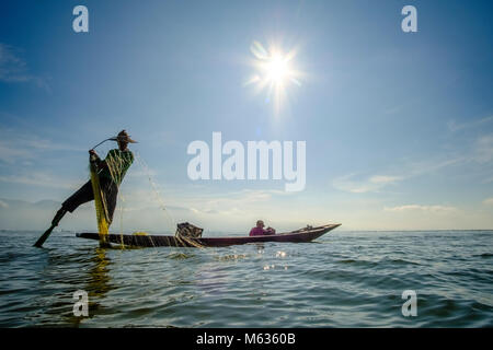 Ein Fischer, stehend auf seinem Boot, Angeln ist die traditionelle Art und Weise auf dem Inle See Stockfoto