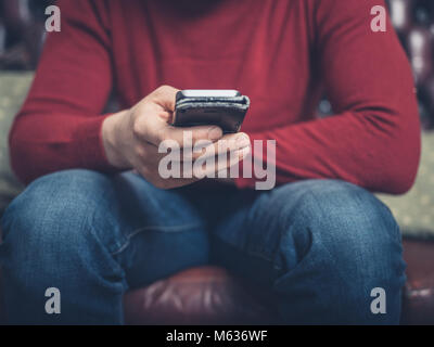 In der Nähe auf einem Mann sitzt auf einem Sofa mit einem Smartphone Stockfoto
