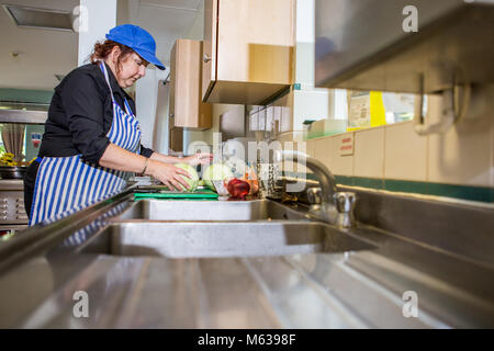 Weiße Frau bereitet das Abendessen in der Küche bei der Arbeit Stockfoto