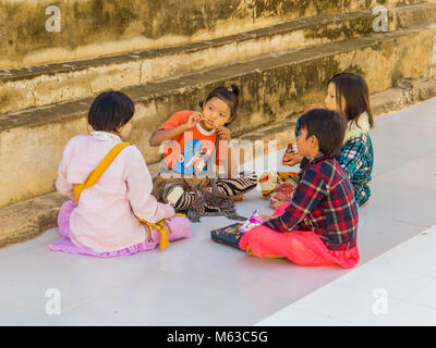 BAGAN, MYANMAR - Januar 6, 2018 Burmesische Kinder außerhalb der Manuha Tempel sitzen. Stockfoto