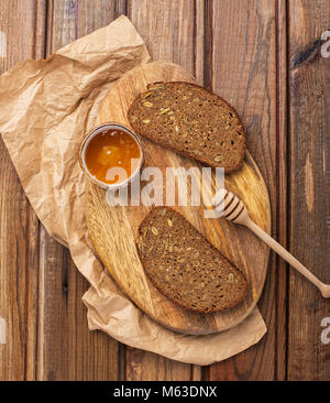 Zwei Stücke von Vollkorn Roggenbrot mit Samen auf Schneidebrett Stockfoto