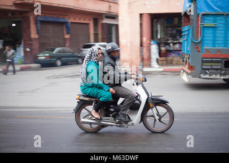 Afrikanischer Mann und Frau Fahrt zusammen mit dem Moped Fahrrad durch Marrakesch Stadtzentrum Stockfoto