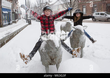 Lockerbie, Schottland, Großbritannien. 28 Feb, 2018. UK Wetter. Schwere Schnee Ursachen red alert in Teilen von Schottland. Schweren Schnee auf Lockerbie fallen. Conor und Lucy Walker sitzen auf dem Schafe Skulpturen in Lockerbie Stadtzentrum. Schottland Kredit: Allan Devlin/Alamy leben Nachrichten Stockfoto