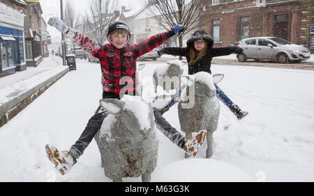 Lockerbie, Schottland, Großbritannien. 28 Feb, 2018. UK Wetter. Schwere Schnee Ursachen red alert in Teilen von Schottland. Schweren Schnee auf Lockerbie fallen. Conor und Lucy Walker sitzen auf dem Schafe Skulpturen in Lockerbie Stadtzentrum. Schottland Kredit: Allan Devlin/Alamy leben Nachrichten Stockfoto