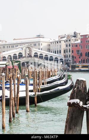 Venedig, Venetien, Italien, 28. Fenbruary 2018. Seltene Schnee in Venedig von der Sibirischen Wetter vorne fegt in Europa verursacht, verschneite Gondeln auf dem Canal Grande in San Polo vor der Rialto Brücke vertäut. Stockfoto