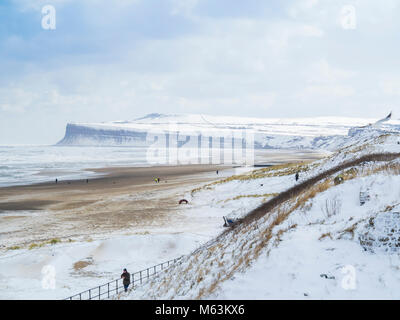 Marske am Meer North Yorkshire UK vom 28. Februar 2018 UK Wetter. Weiterhin Schnee mit einem starken Ostwind sorgen für kalte Bedingungen an einem einsamen Strand mit schneebedeckten Klippen und ein Blick in Richtung Redcar Offshore-windfarm, schwarze Wolken am Horizont weitere Schnee tragen fällt noch kommen. Credit: Peter Jordan NE/Alamy leben Nachrichten Stockfoto