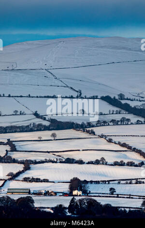 Flintshire, Wales, UK, UK Wetter: Das Tier aus dem Osten weiterhin Chaos in vielen Bereichen in Großbritannien mit Schnee und Temperaturen unter dem Gefrierpunkt zu stiften. Eine gefrorene Schnee bedeckt die Landschaft im ländlichen Flintshire mit der Clwydian Hügel in der Ferne, als die Sonne über dem Bereich mit Sturm Emma arrivng mehr Schnee Stockfoto