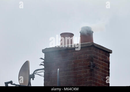 Rauch aus dem Schornstein Topf auf einem Haus in Großbritannien Stockfoto