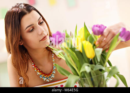 Attraktive Frau arrangieren Tulpen Blumen in Vase Stockfoto