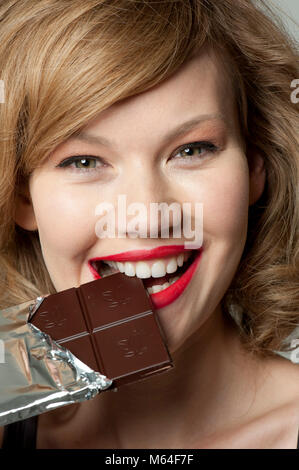Glückliche Frau in bar von dunkler Schokolade beißen Stockfoto
