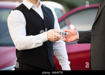 Nahaufnahme der Valet Hand geben dem Auto Schlüssel zum Unternehmer Stockfoto