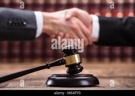 Richter zitternden Hand mit Client hinter Hammer auf hölzernen Schreibtisch Stockfoto