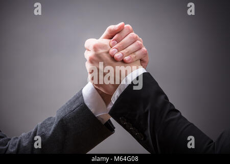 In der Nähe von zwei Geschäftsleuten konkurrieren in den Arm Wrestling auf grauem Hintergrund Stockfoto