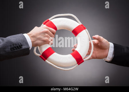 In der Nähe von zwei Geschäftsleute Holding Rettungsring auf grauem Hintergrund Stockfoto