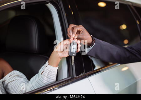 Absatzlage im Autohaus, junge afrikanische Paar erhält der Schlüssel für neue Pkw Stockfoto