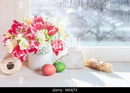 Rosa Tulpen und weiße Freesie Blumen mit Ostern Dekorationen auf dem Fenster, Sonne nach dem Regen Stockfoto