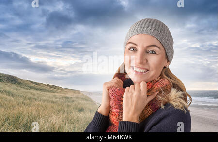 Attraktive Frau mittleren Alters trägt eine gestrickte Gap und farbenfrohen roten Wollschal um den Hals hielt Stand glücklich lächelnd in die Kamera übertreffen Stockfoto
