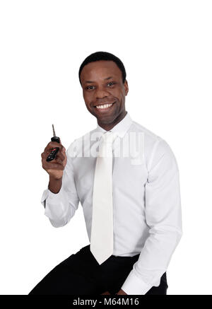 Eine junge schöne afrikanische amerikanische Mann im weißen Hemd und Krawatte, mit seinem neuen Auto Schlüssel, für weissen Hintergrund sitzen Stockfoto