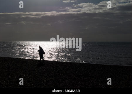 Mann am Strand von glänzende Meer Silhouette, Brighton Stockfoto