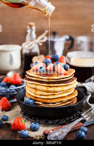 Stapel von frisch zubereiteten Banana Pancakes mit frischen Beeren und Ahornsirup zum Frühstück Stockfoto