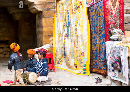 Jaisalmer, Indien - 28 Dez 2018: Kinder in typische Rajasthani indianische Kleidung spielen mit einer Trommel in der Mitte von Jaisalmer Fort. Die Kinder lernen, die Volkslieder, traditionelle Instrumente und Tänze in einem frühen Alter. Sie führen für die Besucher an den verschiedenen Teilen des fort Stockfoto