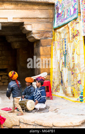 Jaisalmer, Indien - 28 Dez 2018: Kinder in typische Rajasthani indianische Kleidung spielen mit einer Trommel in der Mitte von Jaisalmer Fort. Die Kinder lernen, die Volkslieder, traditionelle Instrumente und Tänze in einem frühen Alter. Sie führen für die Besucher an den verschiedenen Teilen des fort Stockfoto