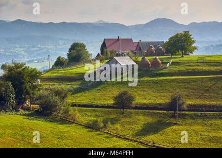 Frühling Landschaft. Traditionelle transsilvanischen Dorf auf einem grünen Hügel in Brasov County, Siebenbürgen, Rumänien. Stockfoto