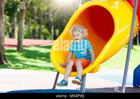 Kids klettern und rutschen auf Spielplatz im Freien. Kinder spielen im sonnigen Sommer Park. Aktivität und Amusement Center in Kindergarten oder Schule Hof. Chi Stockfoto
