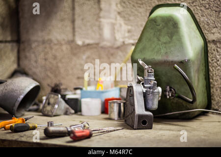 Kleine Vergaser mit Luftfilter und Kraftstofftank von alten italienischen Motorrad Roller auf der Workbench mit mehr Teile und Werkzeuge Stockfoto