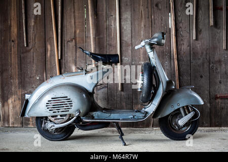 Scheune finden Sie alte, rostige blau-grau Original Lack italienische Motorrad Roller parken auf Holz Wand der Hütte Stockfoto