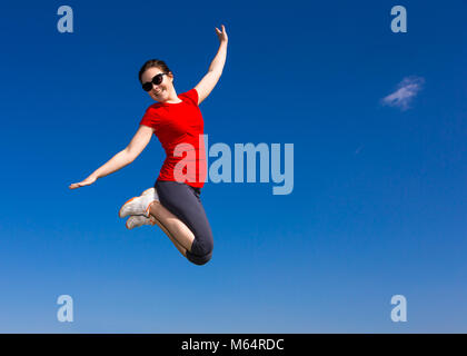 Junges Mädchen springen im Freien gegen den blauen Himmel Stockfoto