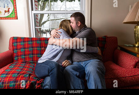 Eine Junge kaukasier Paar wartet aufgeregt und betet für eine gute Nachricht, da Sie sitzen auf Ihren Wohnzimmer Couch. Stockfoto