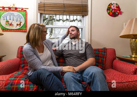 Eine Junge kaukasier Paar wartet aufgeregt und betet für eine gute Nachricht, da Sie sitzen auf Ihren Wohnzimmer Couch. Stockfoto