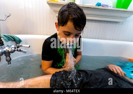 Twin kaukasischen Brüder spielen in Ihrer Wasser gefüllten Badewanne zusammen mit ihrer Kleidung an Stockfoto