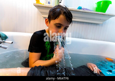 Twin kaukasischen Brüder spielen in Ihrer Wasser gefüllten Badewanne zusammen mit ihrer Kleidung an Stockfoto