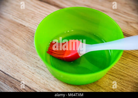 Grüne Schüssel mit Öl und roten Gebäck Bürste Stockfoto