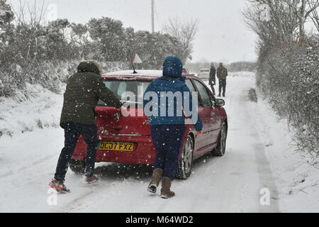 Die Menschen drücken Sie ein Auto, das auf der A 30 in der Nähe von Land's End in Cornwall gestrandet nach schweren Schnee, die Fahrbedingungen erschwert. Stockfoto