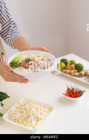 Köchin traditionelle vietnamesische Suppe pho bo mit Kräutern, Fleisch, Reis Nudeln Stockfoto