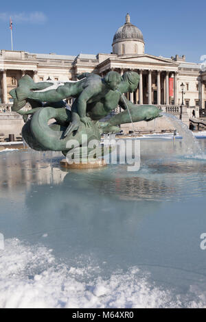 Schnee auf dem Trafalgar Square und der National Gallery und Eiszapfen auf dem Brunnen. Stockfoto